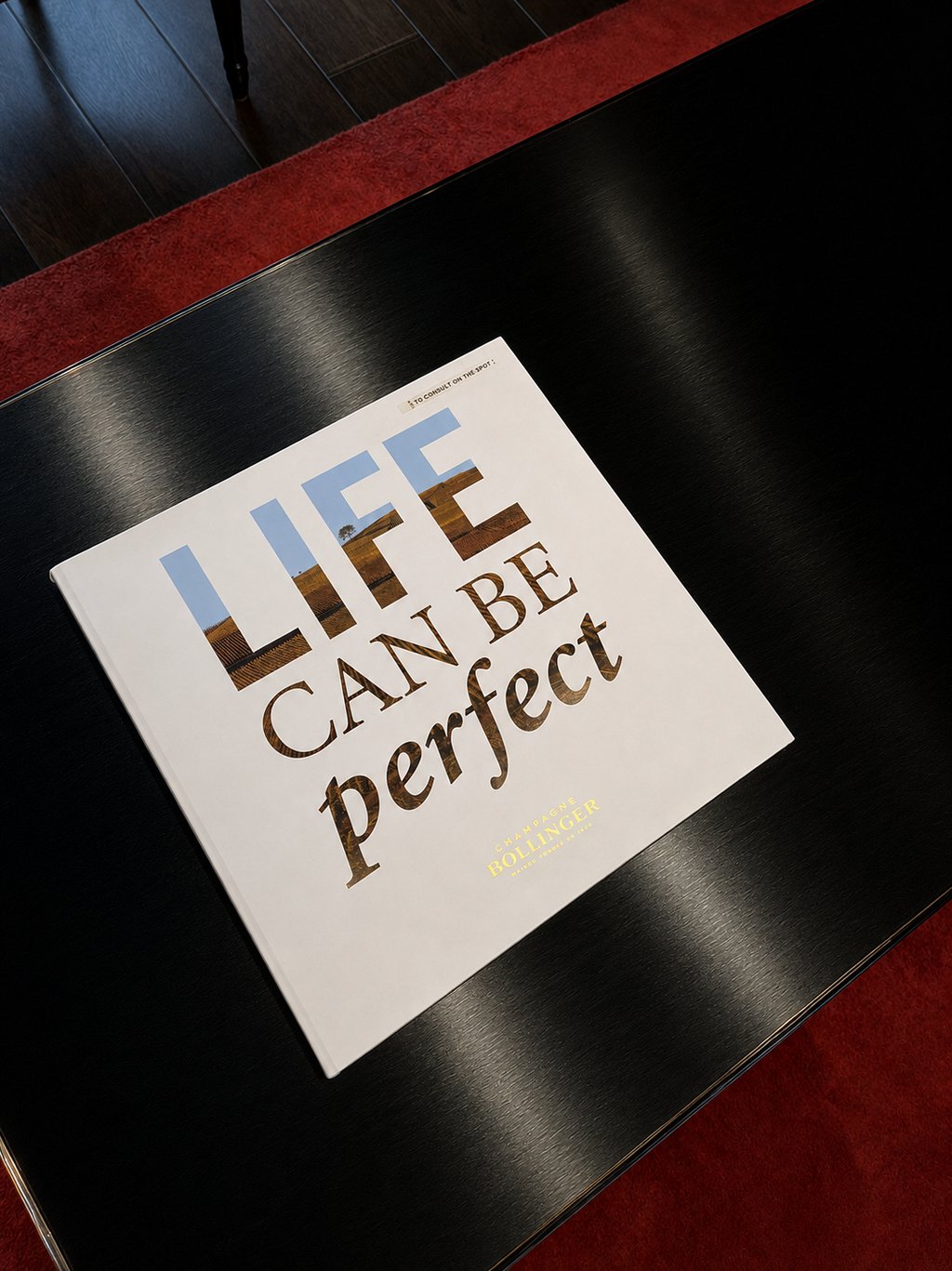 Champagne Bollinger coffee table book on a glossy black surface, creating a refined luxury lifestyle scene.