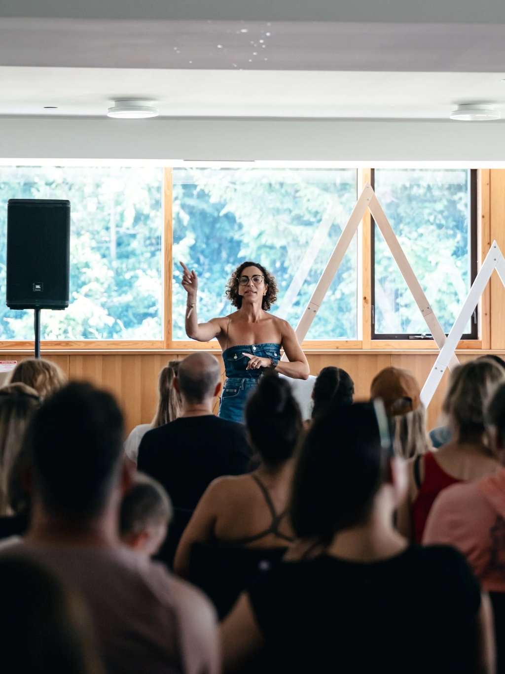 A female motivational speaker at an indoor business workshop event with headset beside speaker
