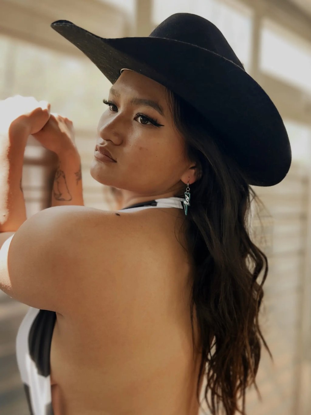 Amelia posing in a horse trailer with a black cowboy hat on