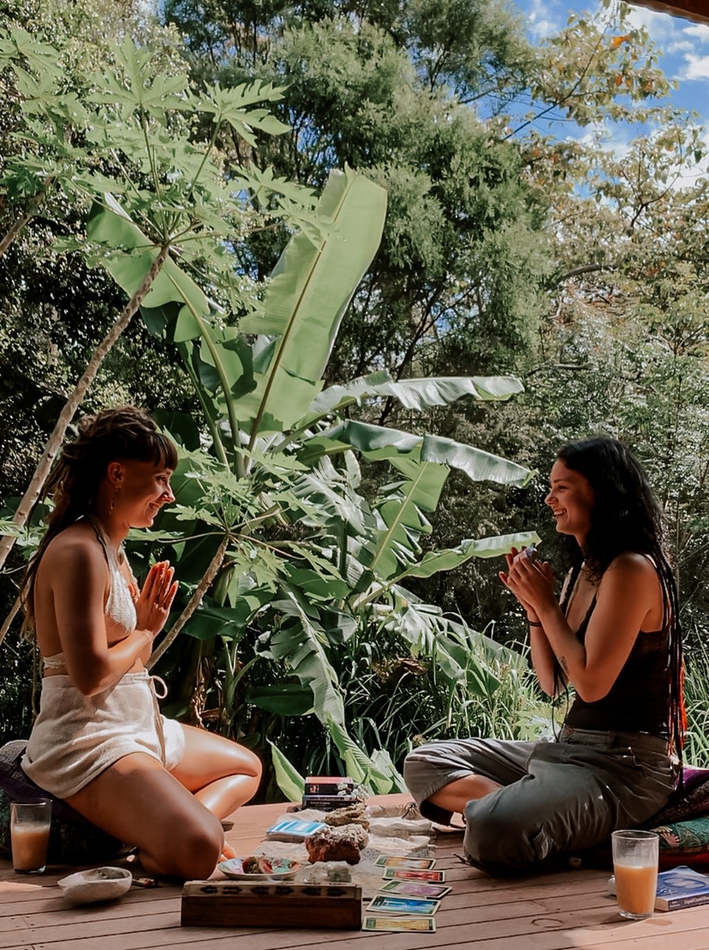 two women sitting on a deck with a cup of tea and tarot oracle cards