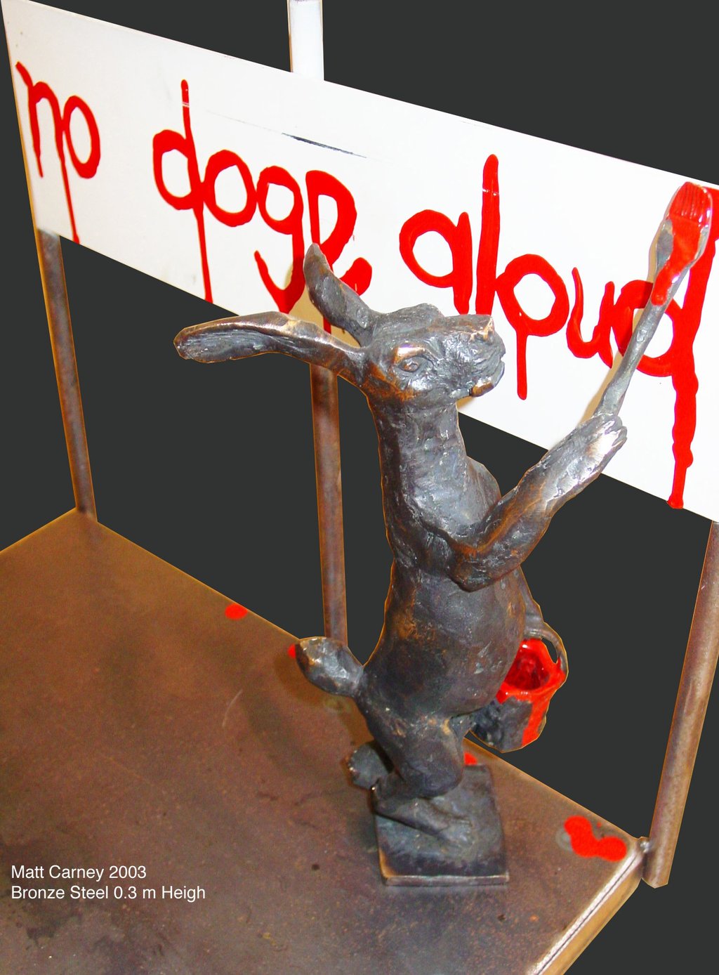 a statue of a rabbit painting a sign that says no dogs alloud