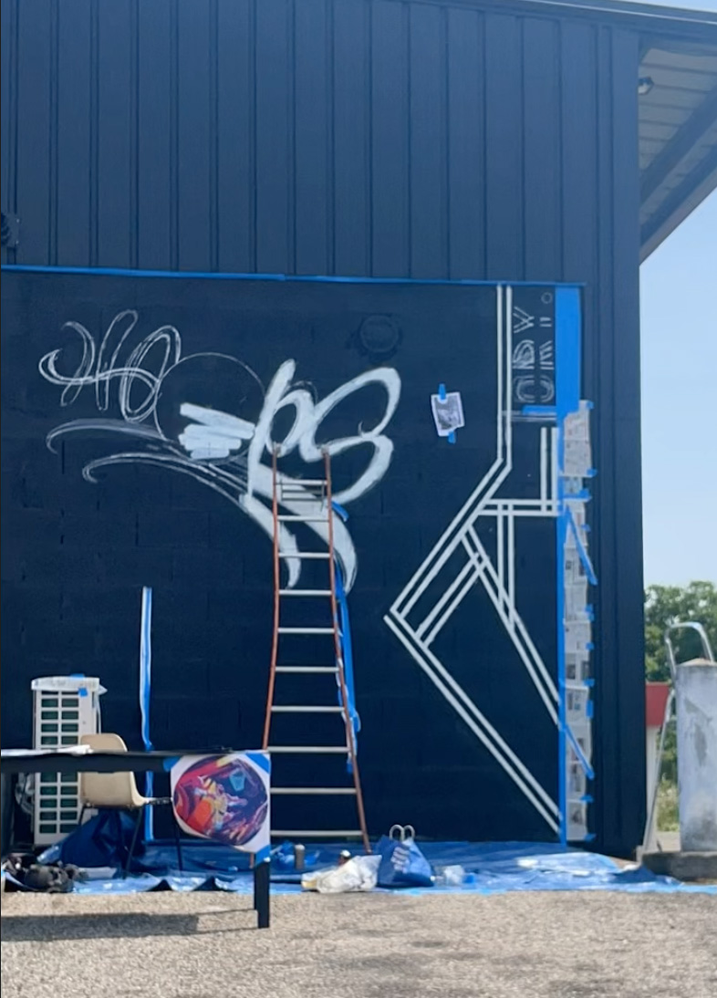 un mur noir avec le début d'un graffiti blanc