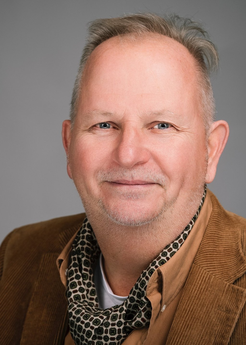 professioneel portret van lachende man met colbert en sjaal in studio in Raamsdonksveer