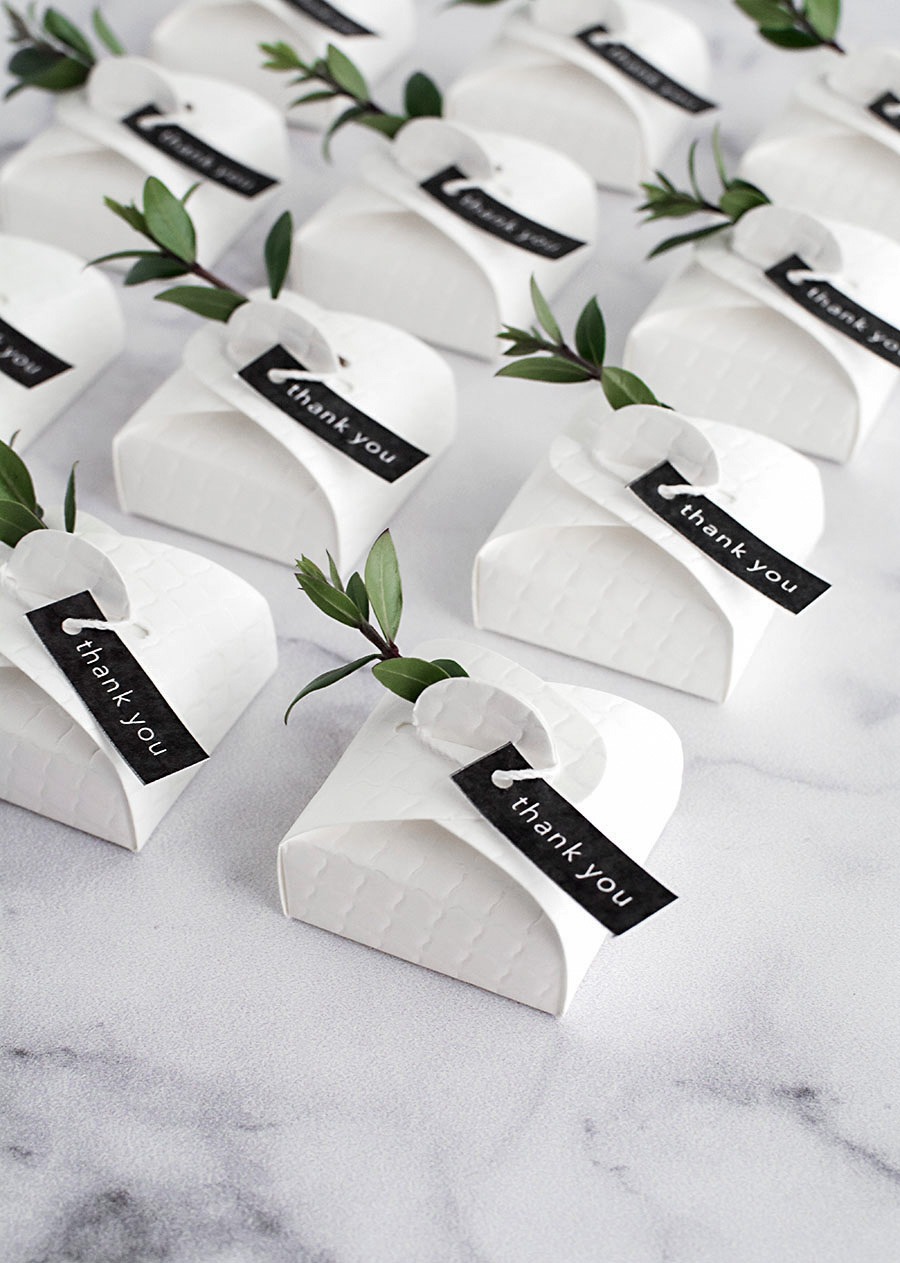 a table with a bunch of small white paper wedding favour boxes