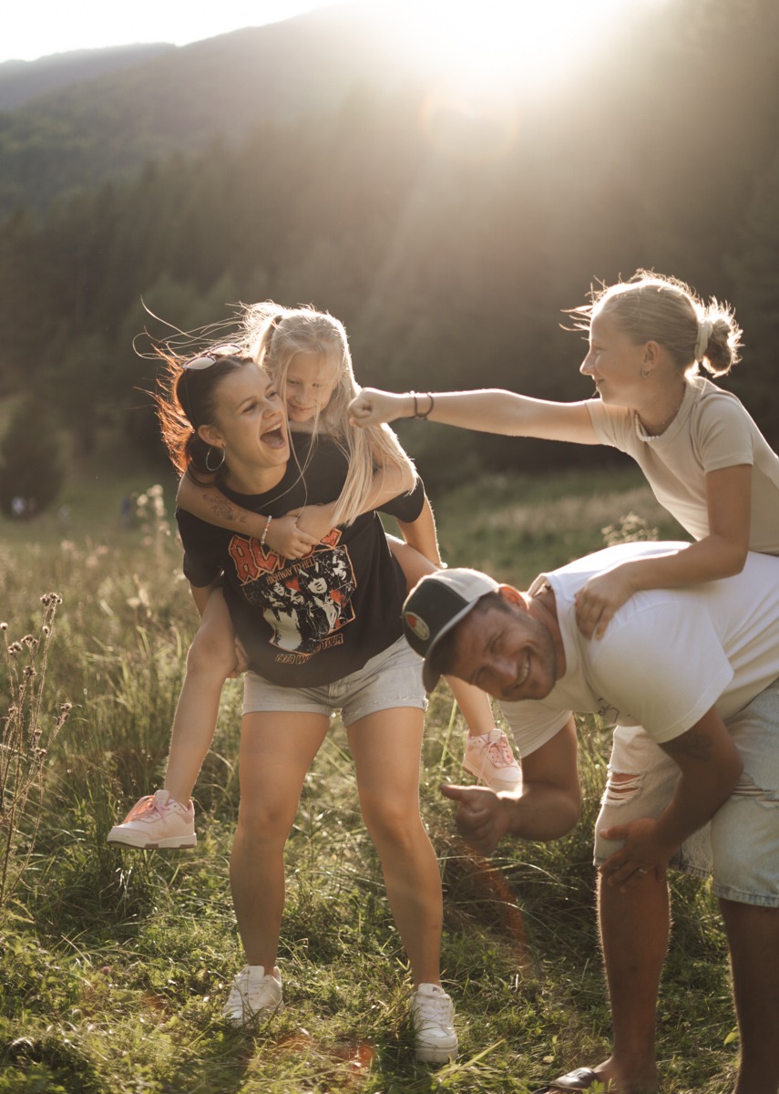 Smiling family in the field holding daughters on their back