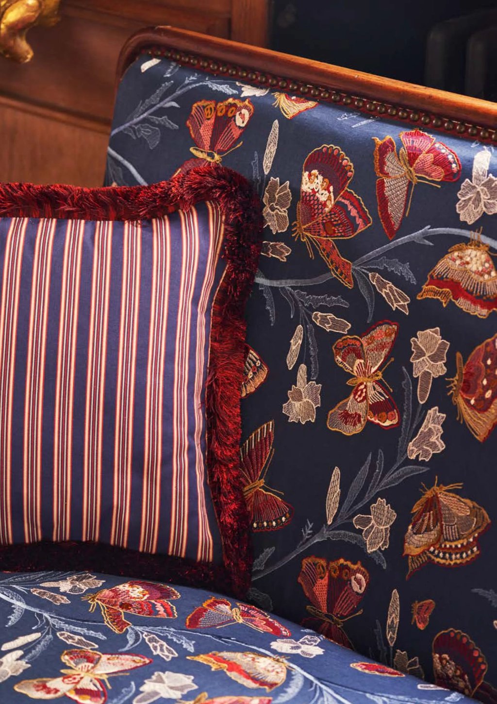 Banquette couverte d'un tissu bleu aux papillons et un coussin à rayures et marabout rasé