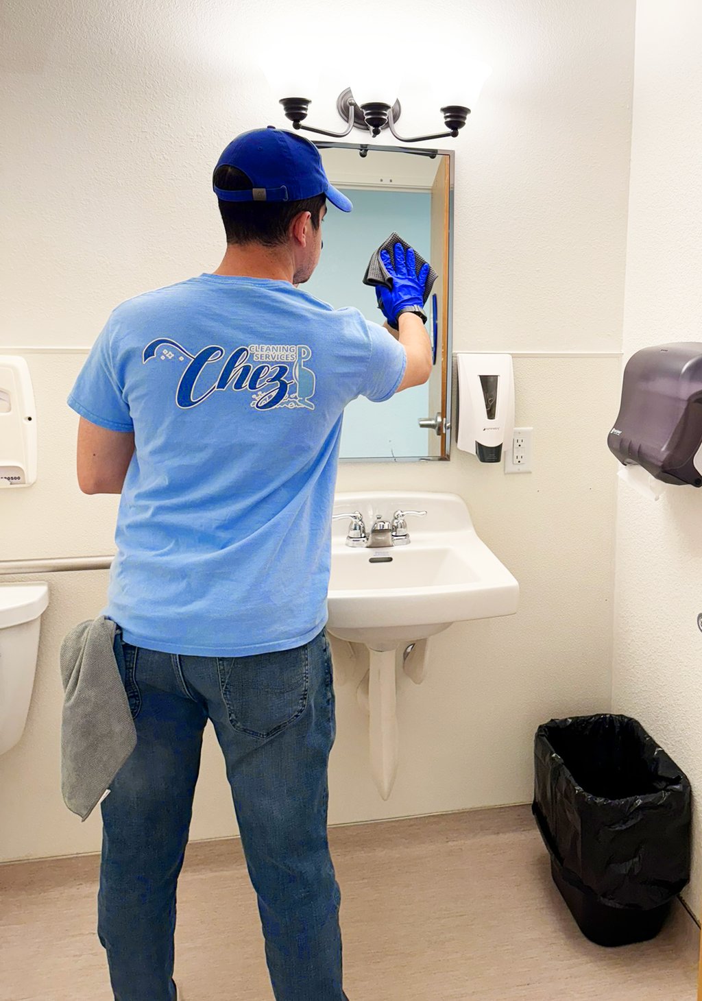 Janitor from Chez Cleaning Services cleaning a mirror in a bathroom