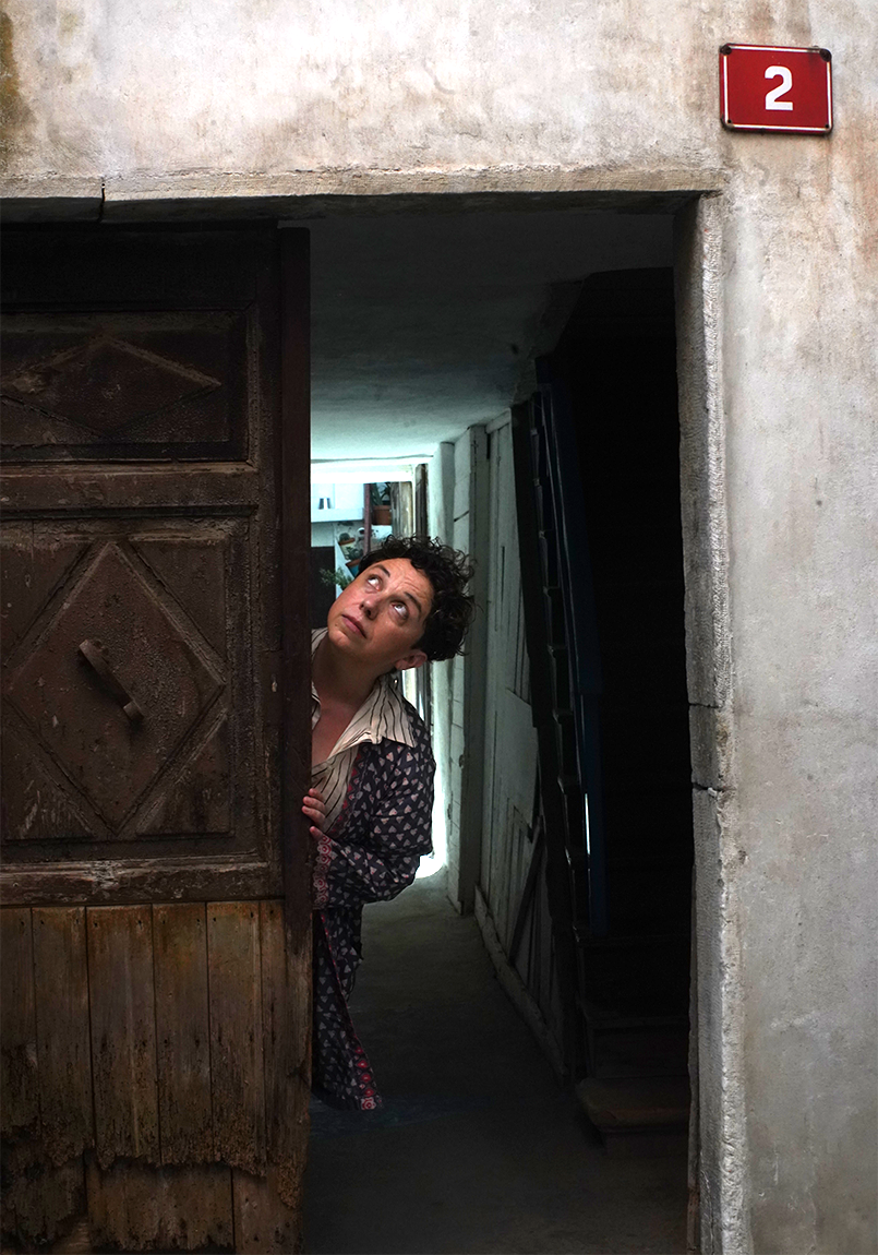 Marisa hiding in an old european doorway, looking up to her right