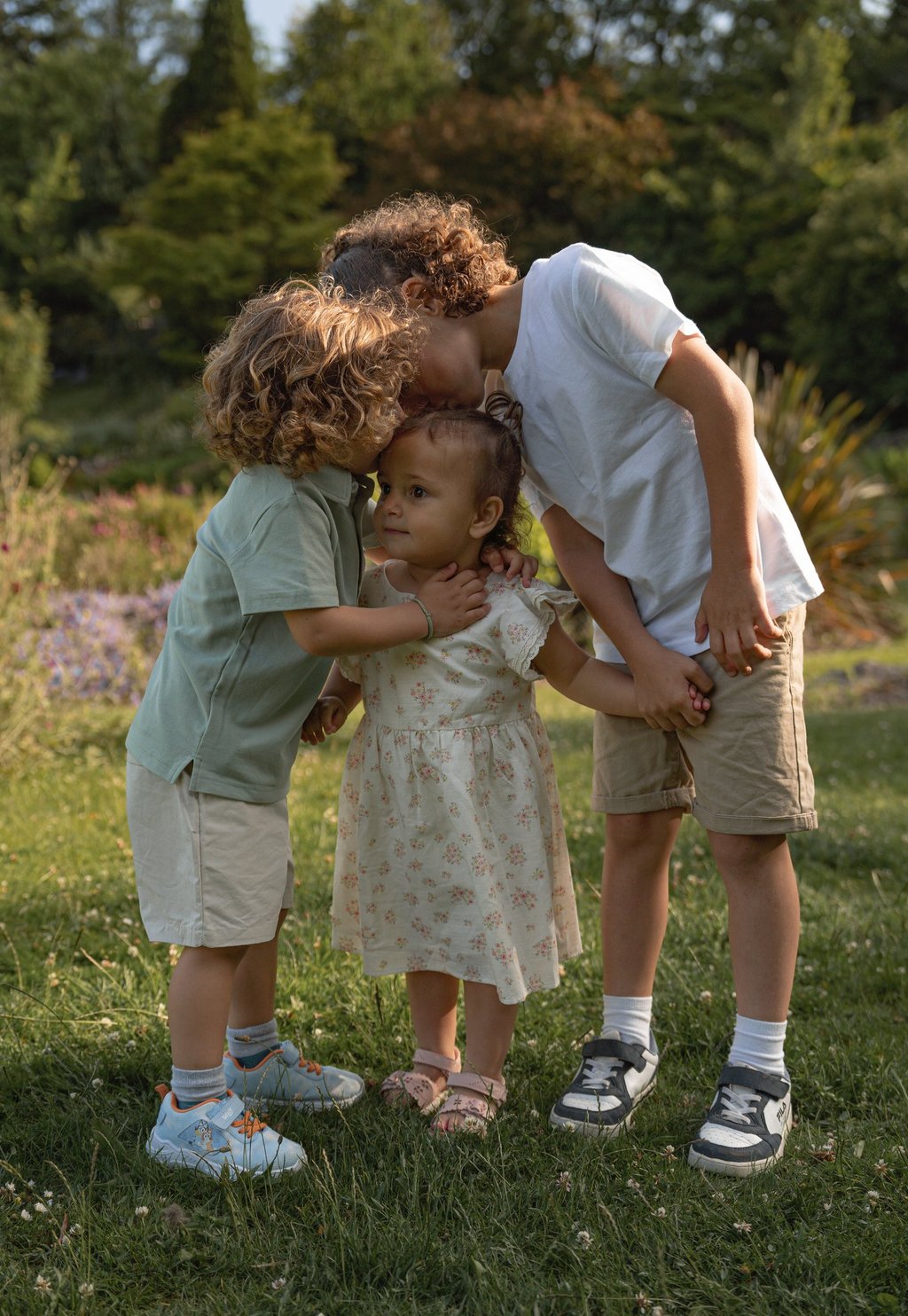 two brother kissing and hugging little sister holding hands