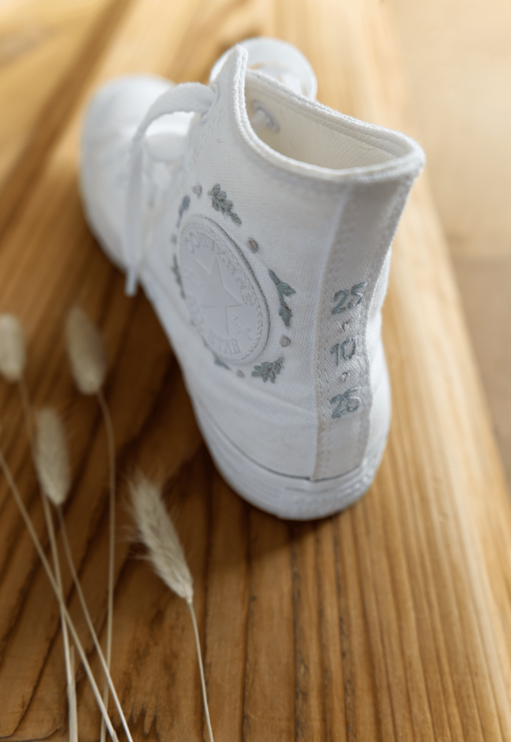 Weisser Converse mit Stickerei, Hochzeitsdatum und floralen Mustern.