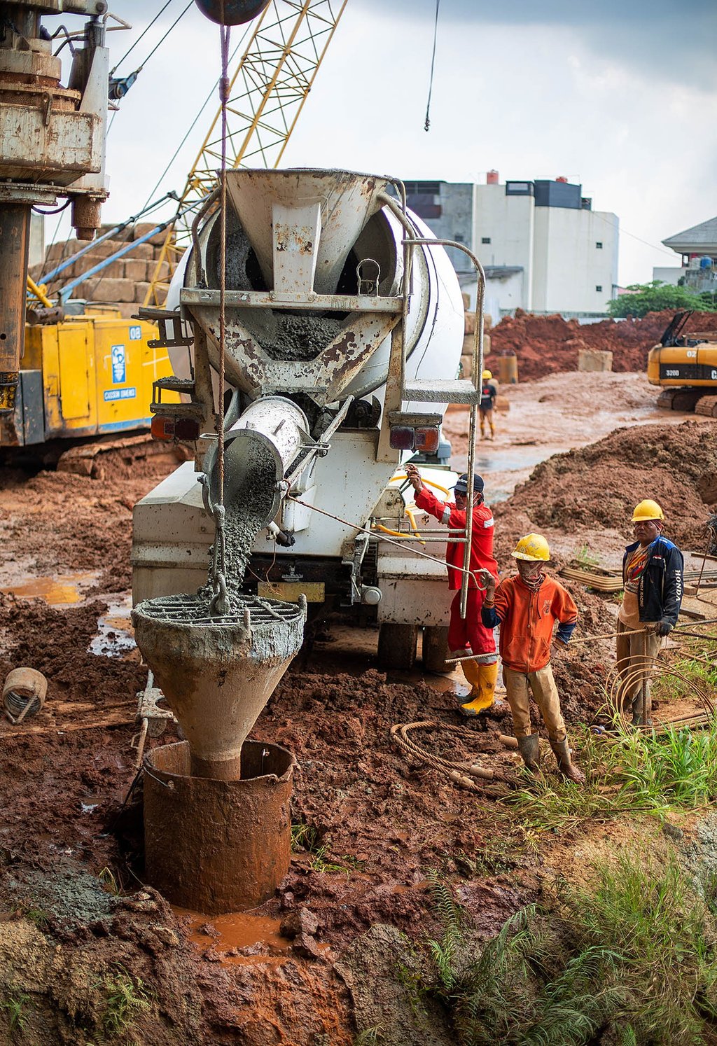 mesin pengaduk semen sedang dijalankan oleh seorang pekerja konstruksi. jasa photography jakarta