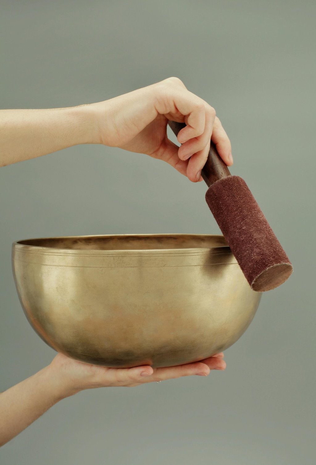 a person holding a singing bowl with a hand holding a small object