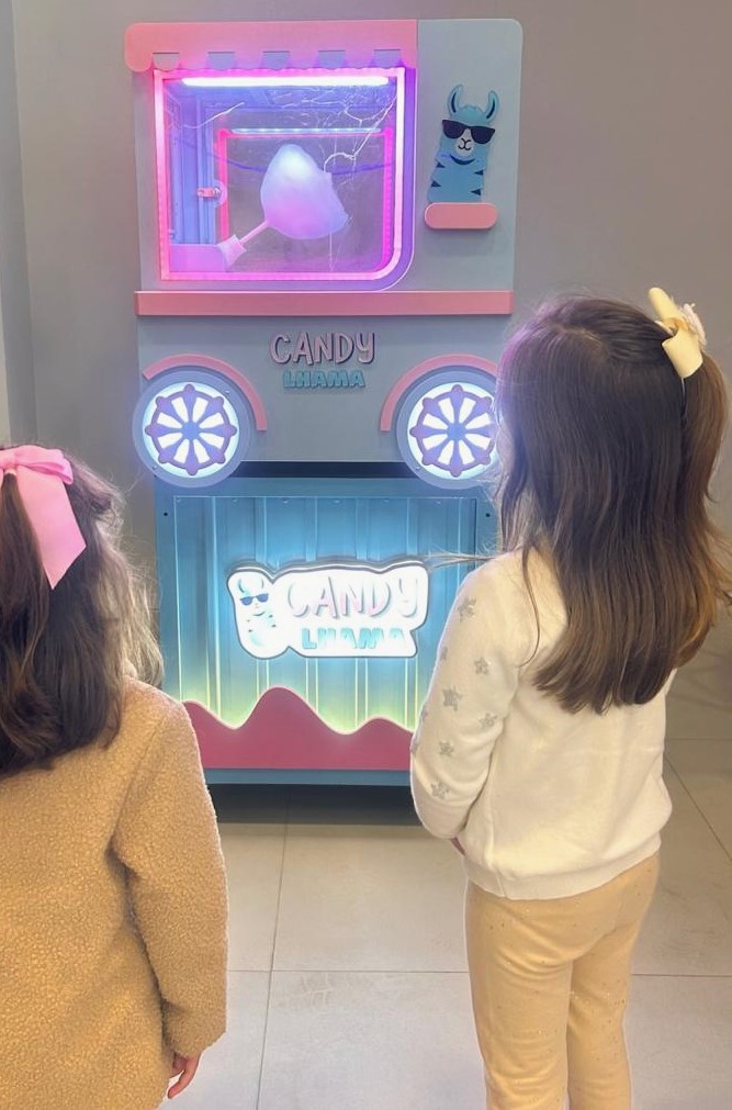 duas meninas observam o algodão doce ser produzido na máquina