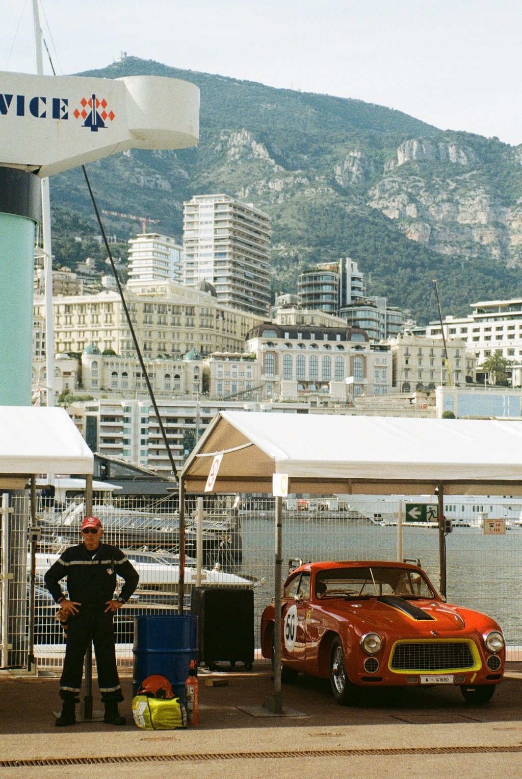 a race car parked in the paddock with a man stood next to it