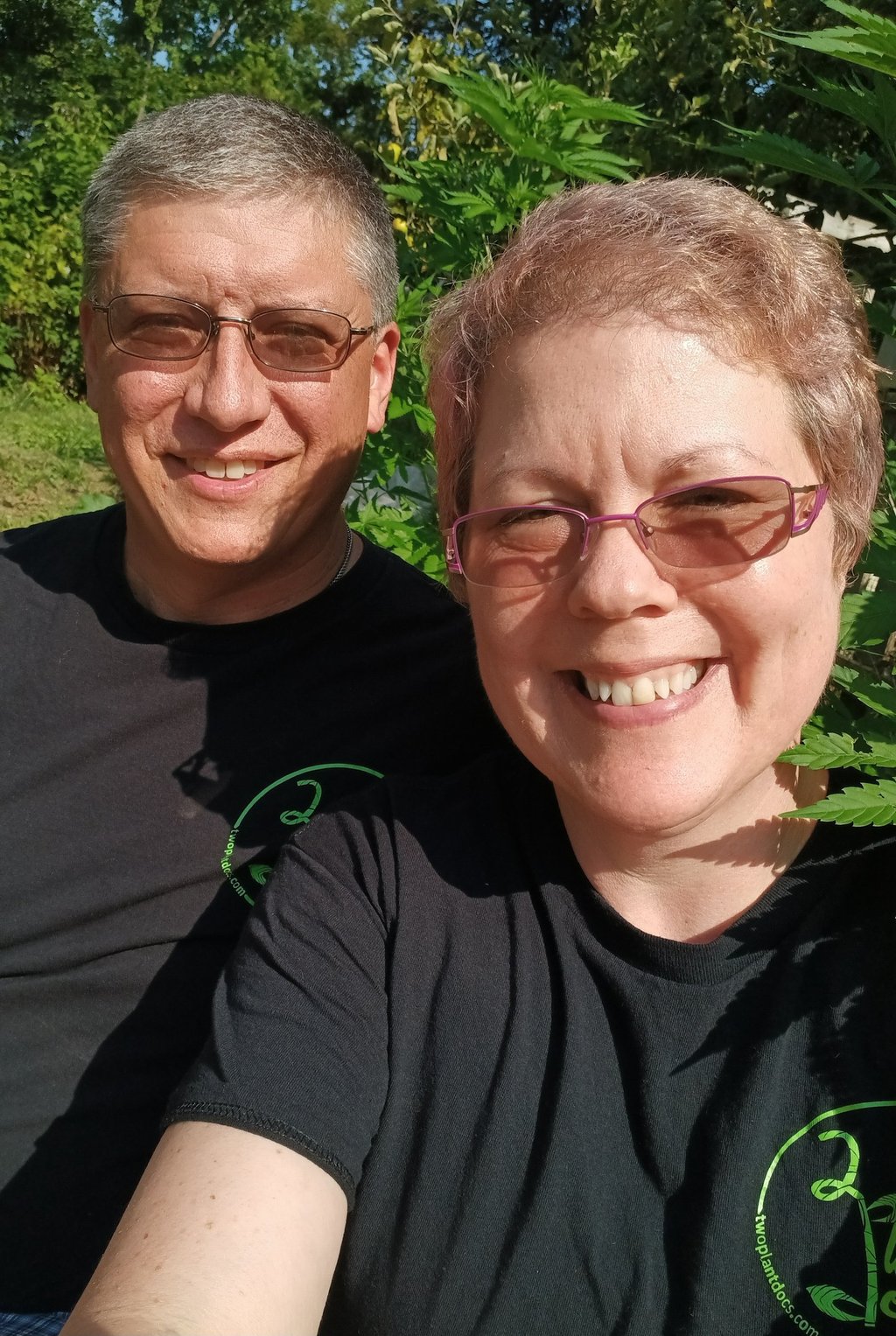 a man and woman sitting in front of a hemp plant
