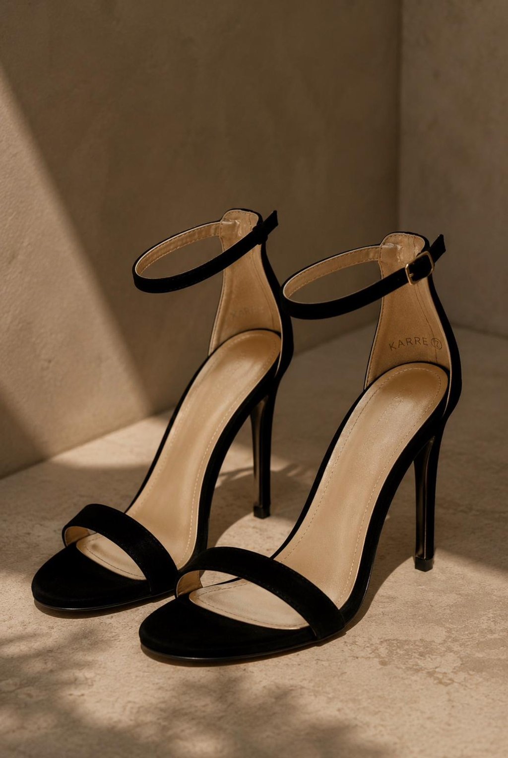 Black stiletto heels with ankle straps styled in warm natural sunlight on a neutral luxury-inspired