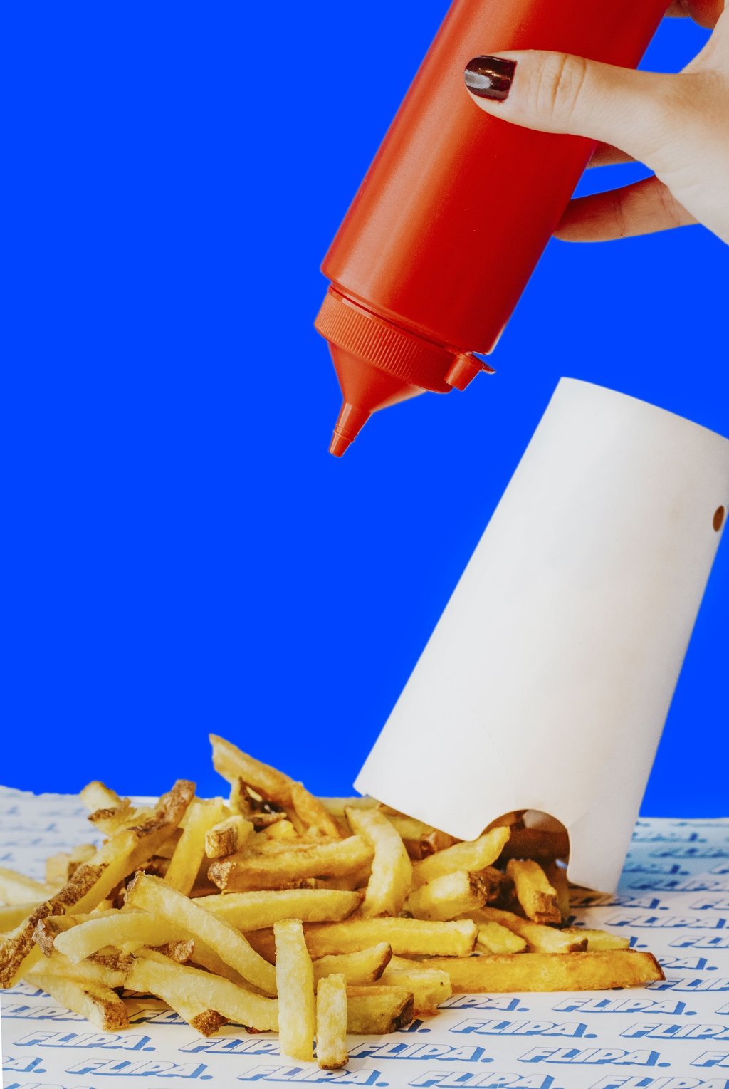 Patates fregides casolanes de Flipa amb ketchup sobre fons blau