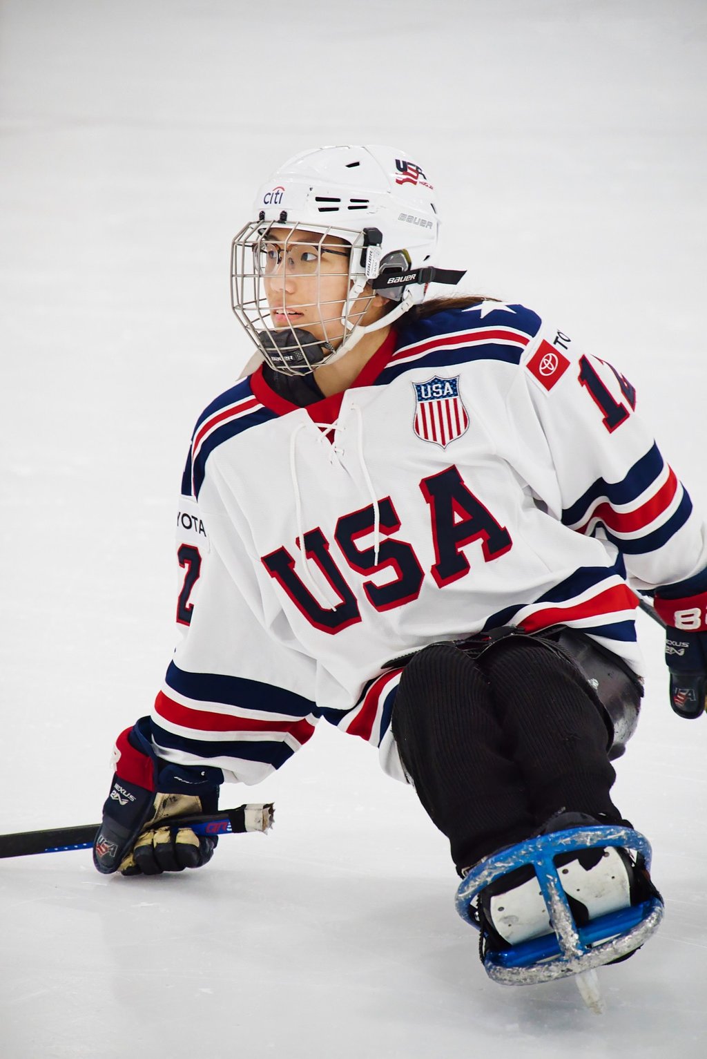 a sled hockey player in a white USA jersey and a hockey helmet