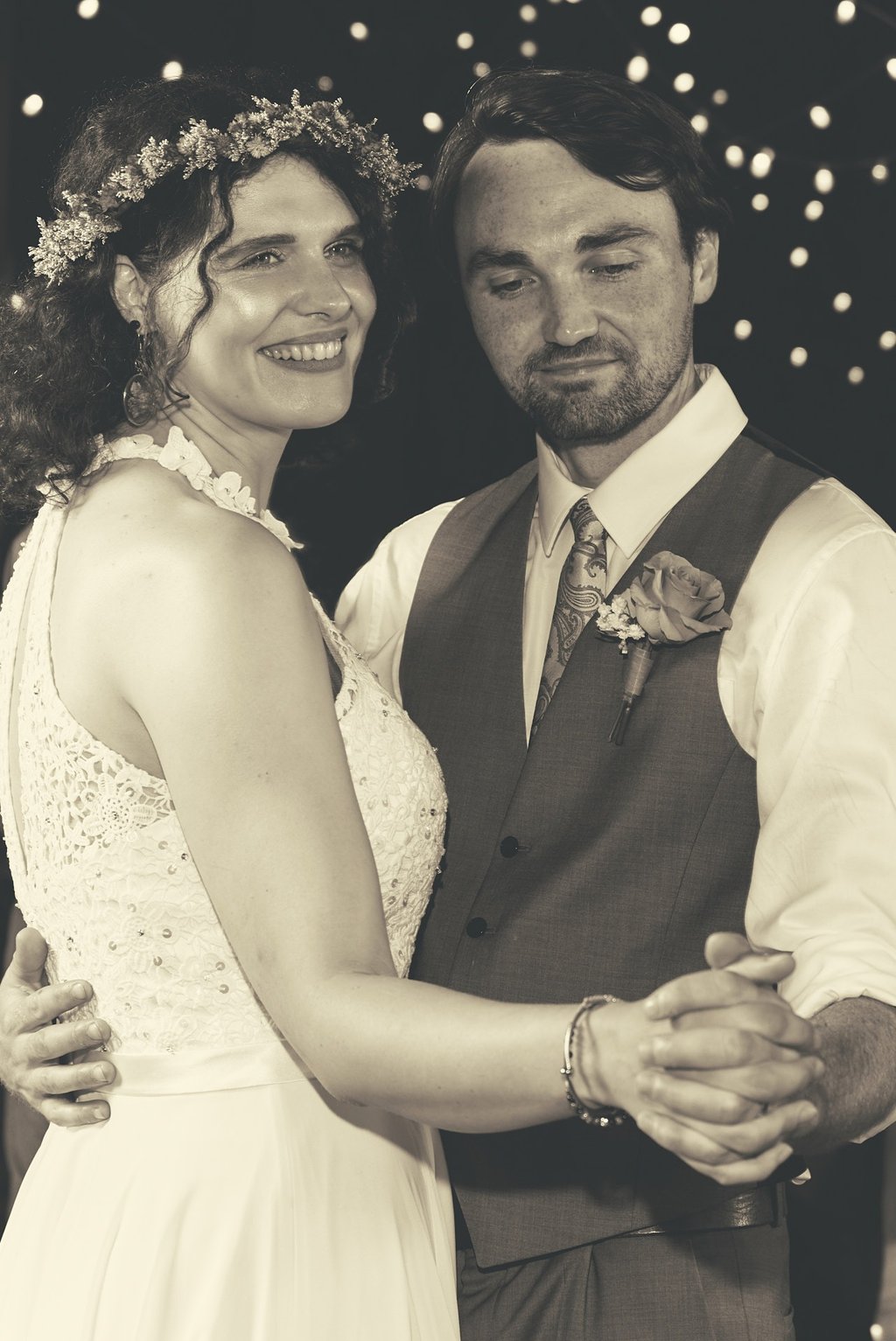 a bride and groom dancing at a wedding reception in a barn with lights