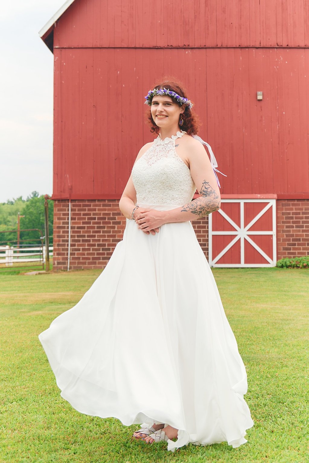 a woman in a white dress standing in front of a barn