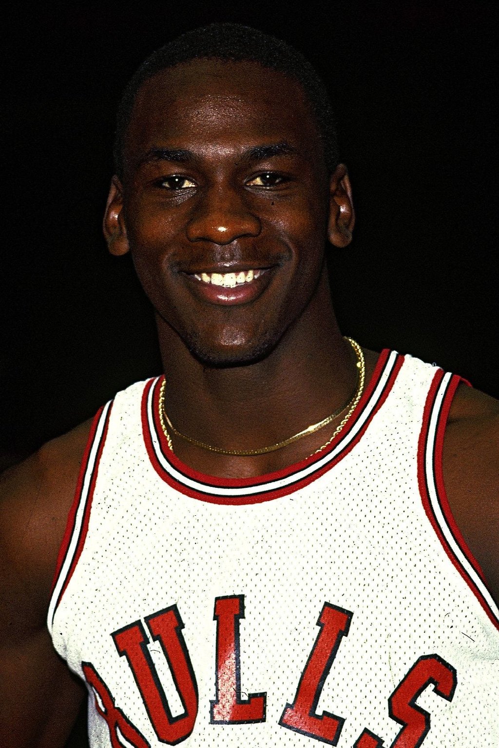 Michael Jordan smiling in his Chicago Bulls white home jersey during his 1984-85 NBA rookie season