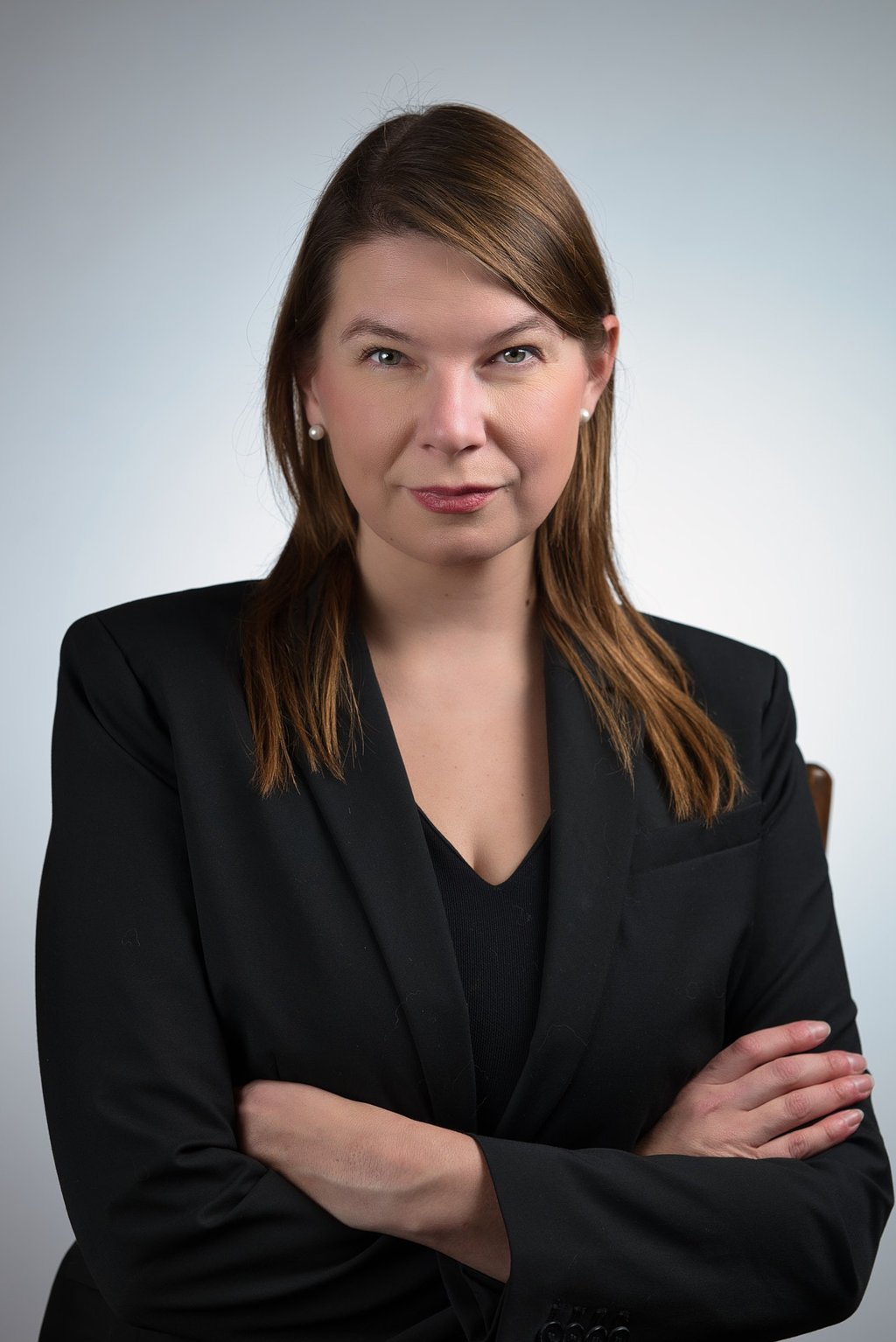 a woman in a black suit and a black shirt looking confident