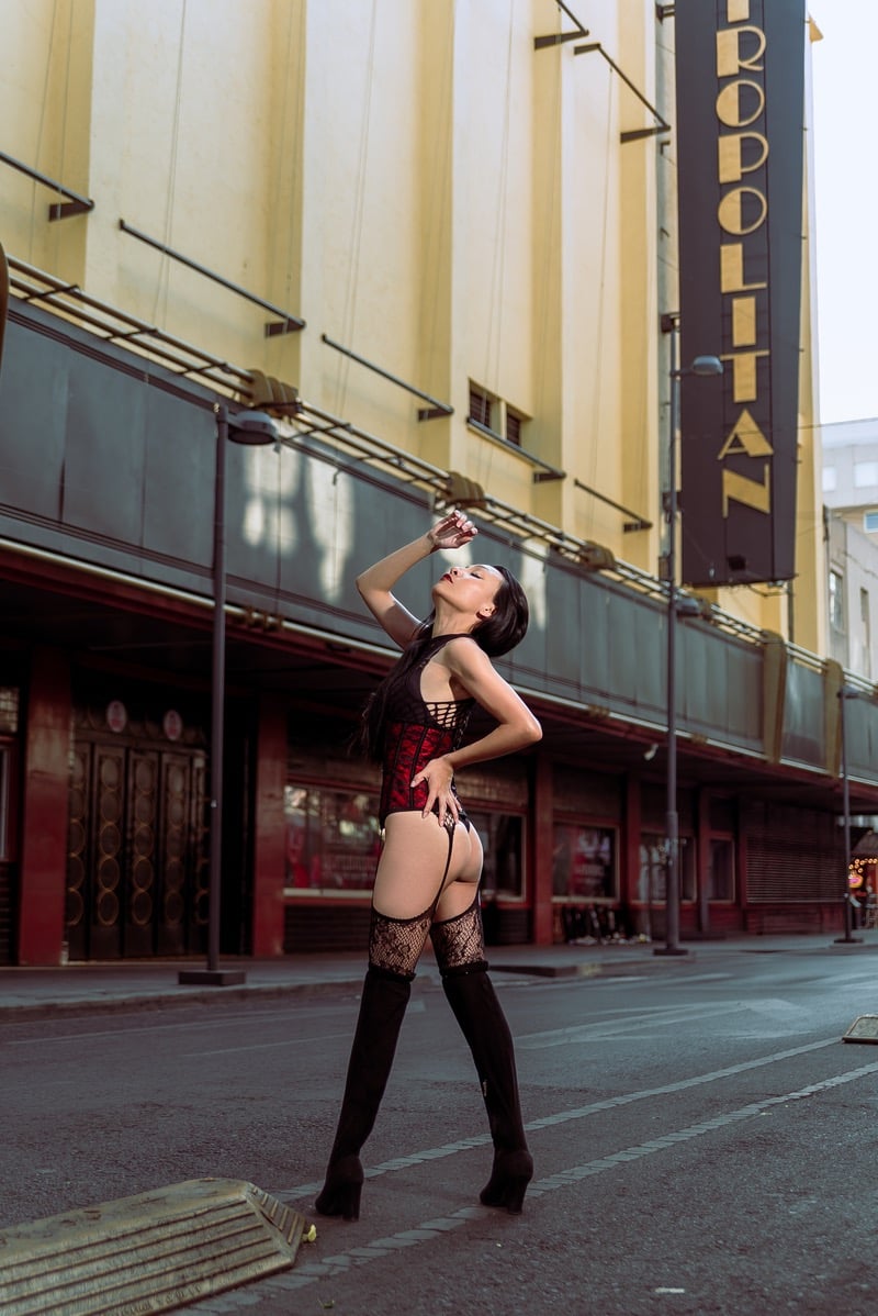 A model in a red corset and black lace stockings poses outside the Metropolitan theater.
