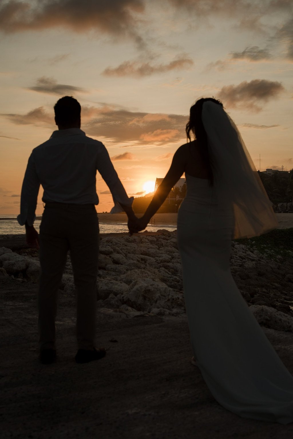 Silhouette of a couple holding hands during sunset prewedding photoshoot at Apurva Kempinski Bali beach