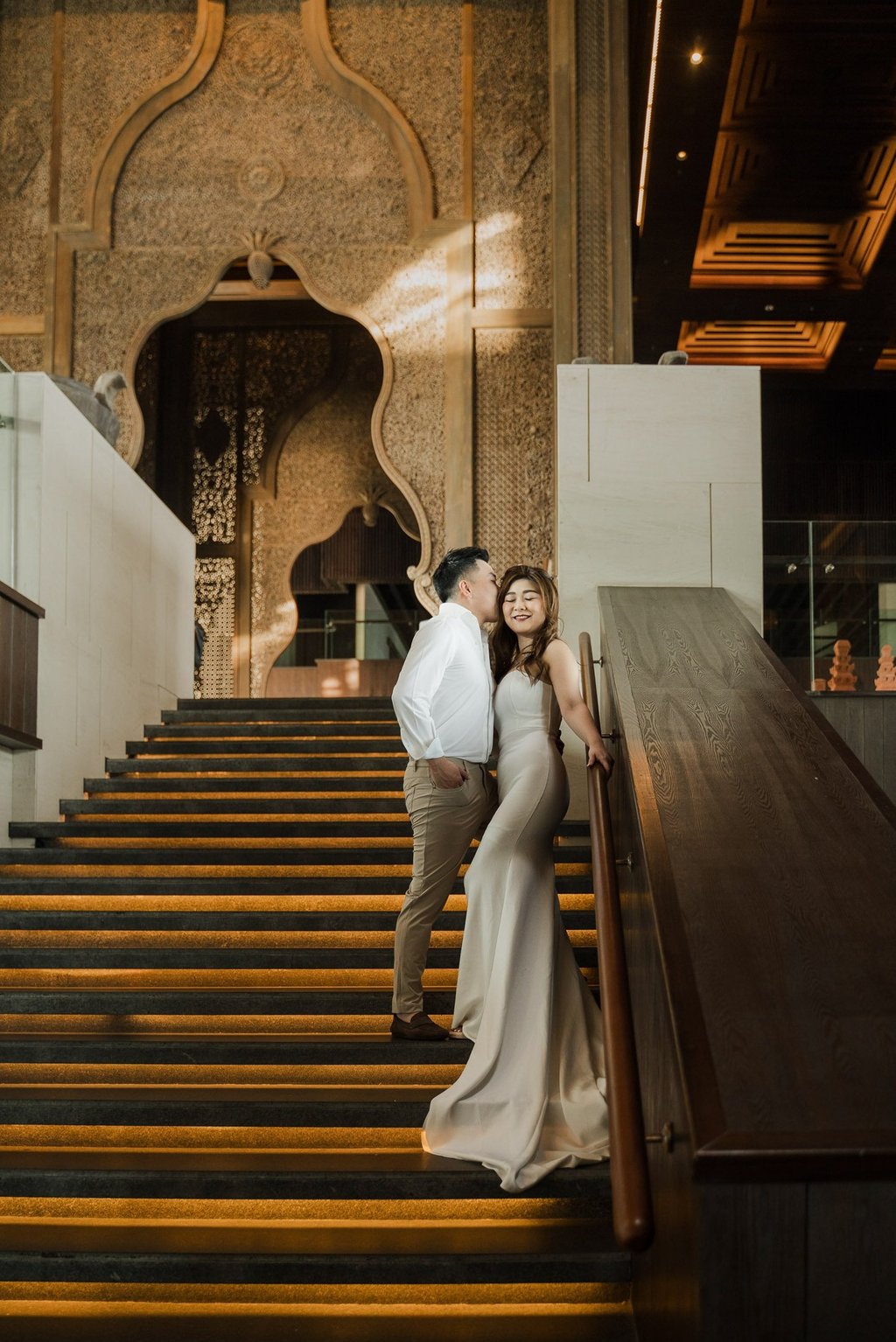 Couple standing on the iconic grand staircase during a prewedding photoshoot at Apurva Kempinski Bali