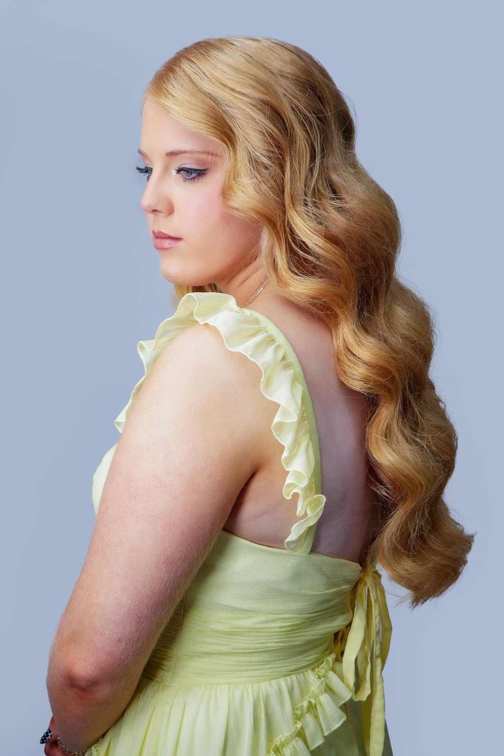 Bride with redhead hair styled in glam waves, wearing yellow dress, soft wedding makeup with neutral tones and long lashes.