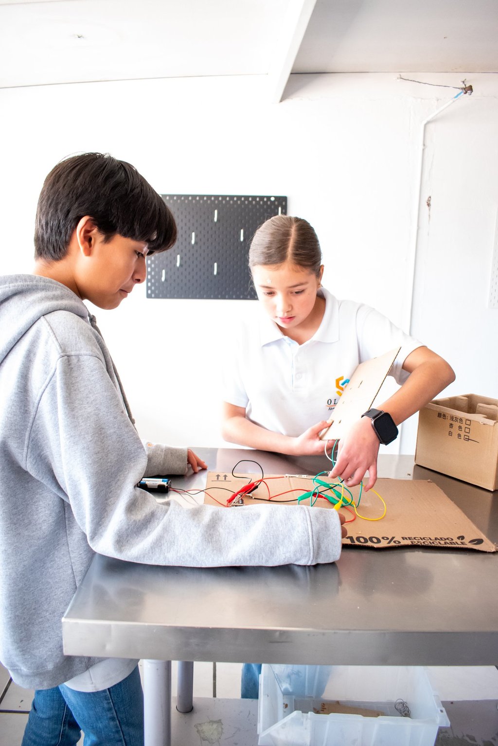 Students collaborating on a STEM project with an electrical circuit and wires in a classroom workshop.