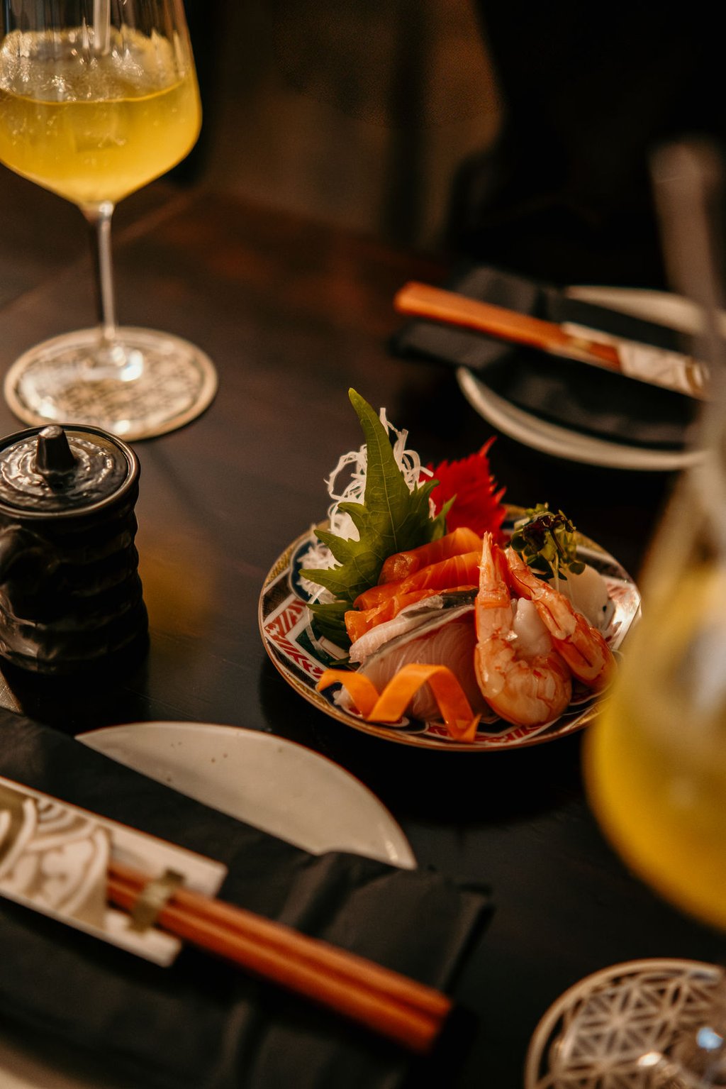 Fresh sashimi platter with salmon and prawns served on a ceramic plate with Japanese cocktails.