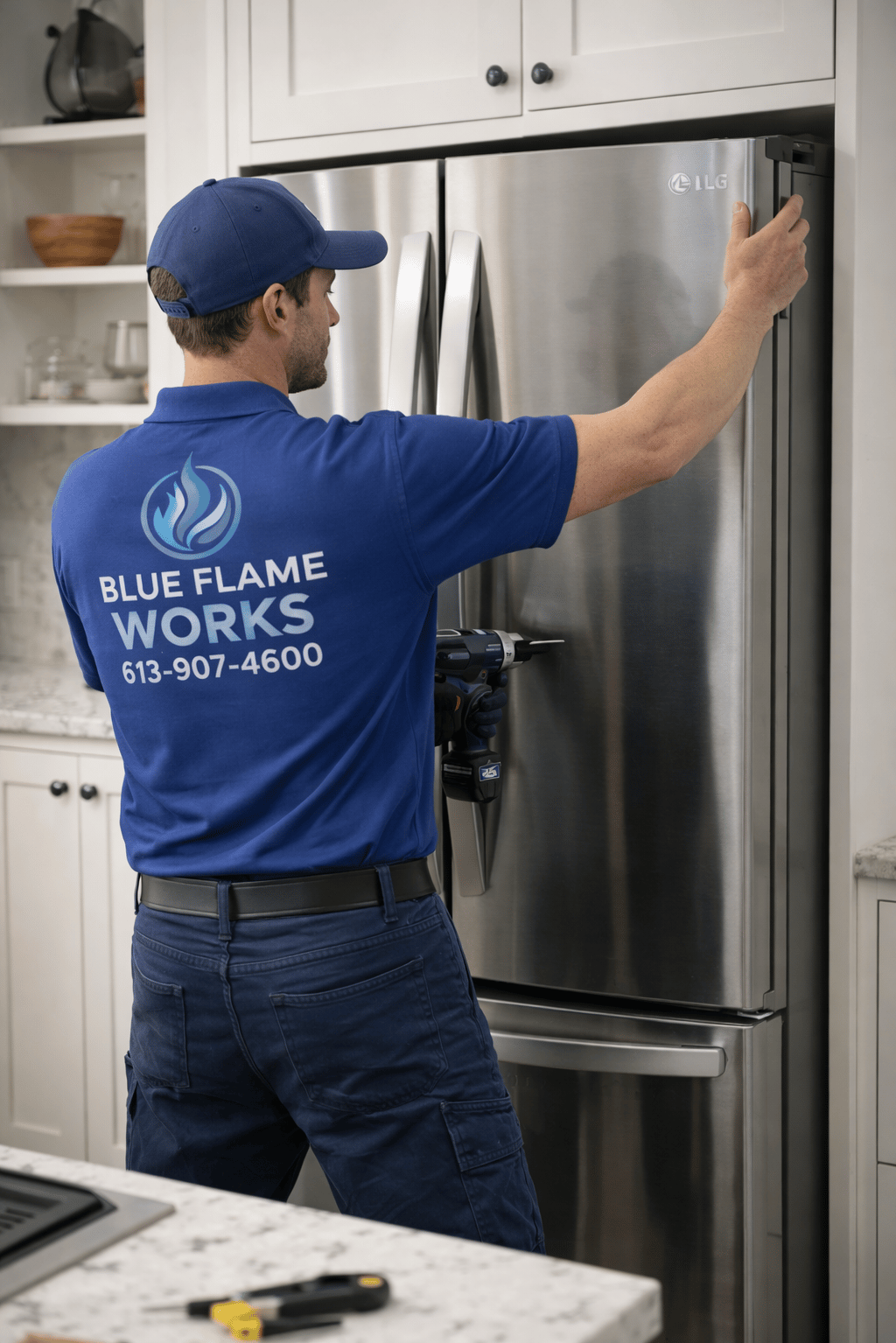 Blue Flame Works tech installs an LG fridge in a bright modern kitchen wearing a branded blue shirt.