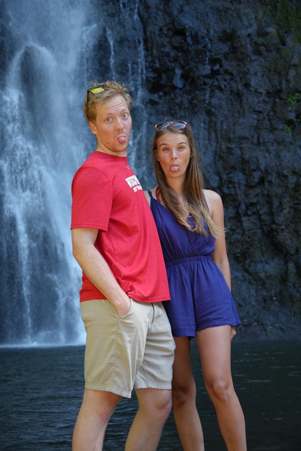 Alex and Niccy sticking out their tongues in front of a waterfall in Tahiti