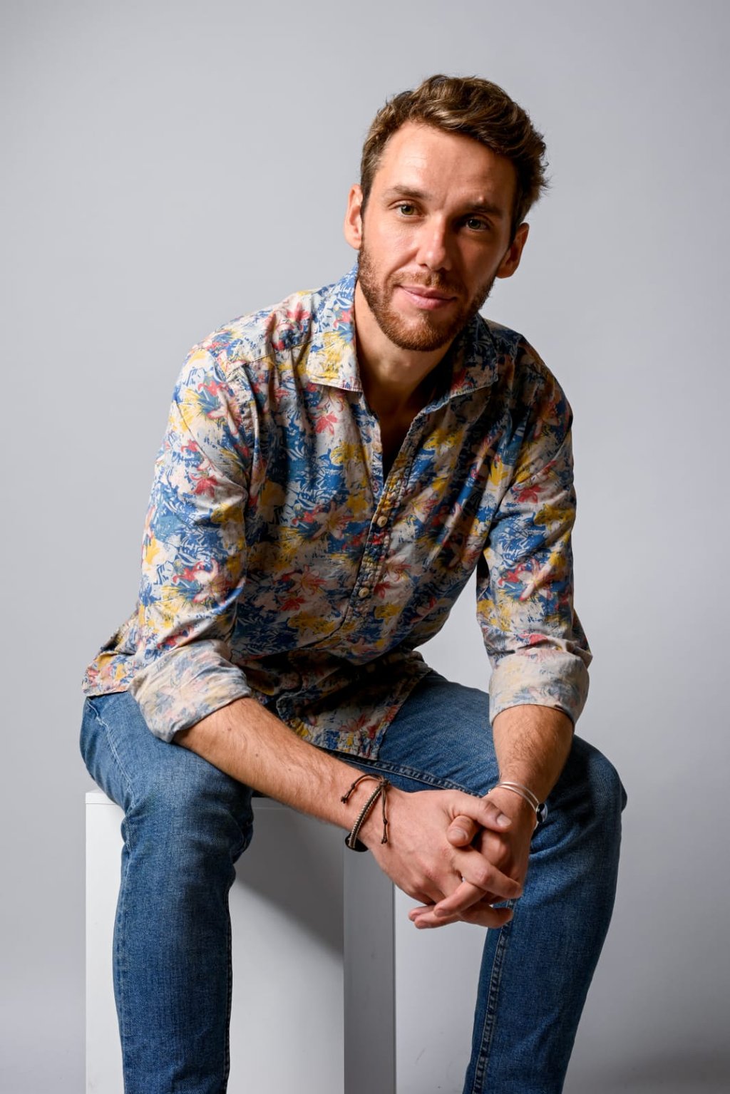 Monsieur rêve architecte, vêtu d'une chemise boutonnée à imprimé floral coloré et d'un jean bleu