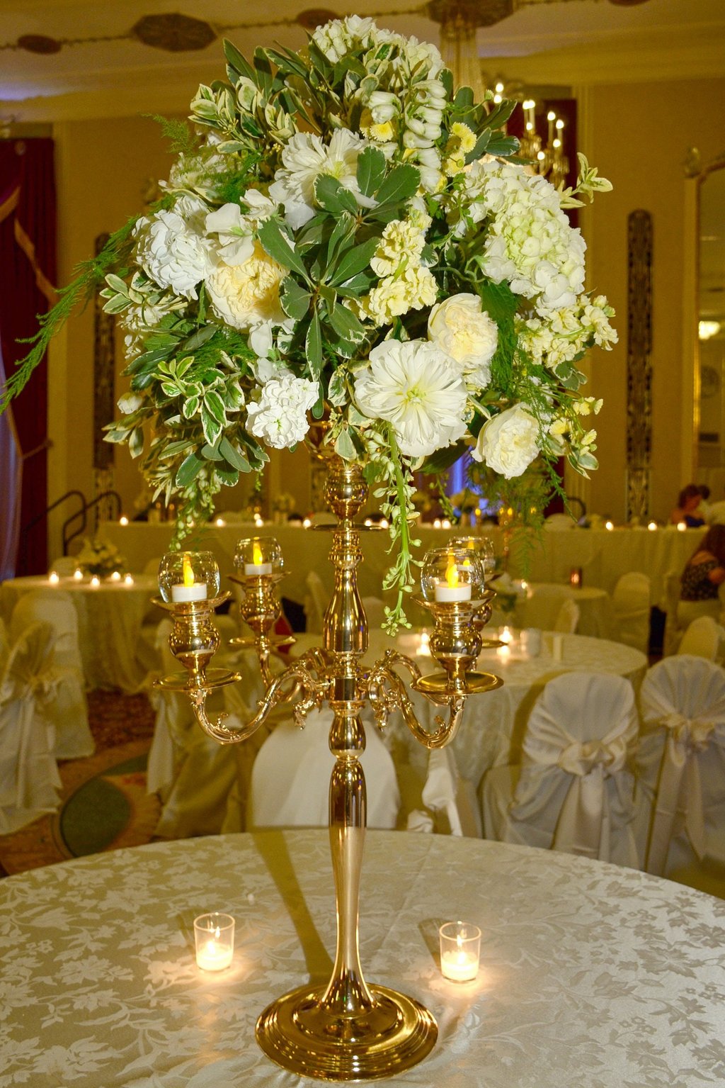 a tall gold fancy candle holder with candles and flower