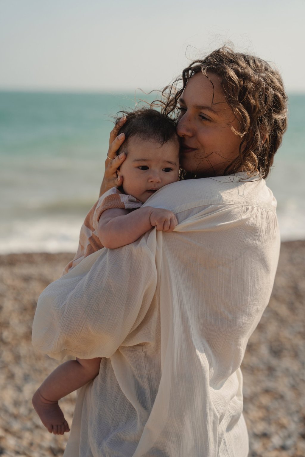 woman holding baby by the sea