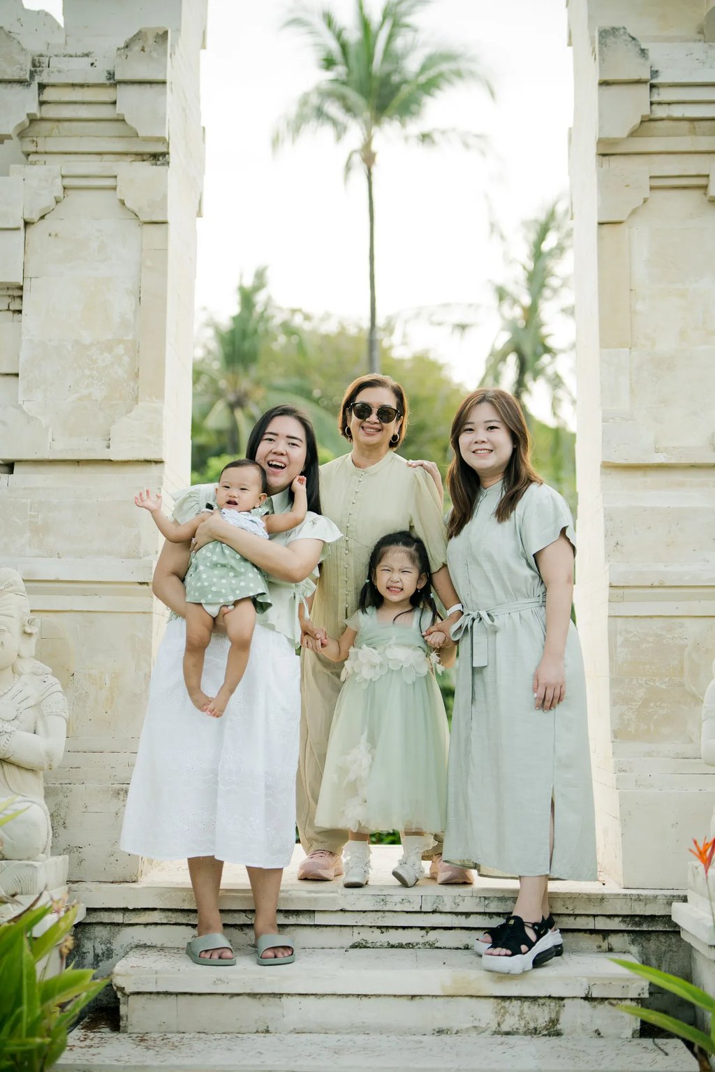 Mother and daughters posing together at a traditional Balinese entrance during a family photography session in Bali.