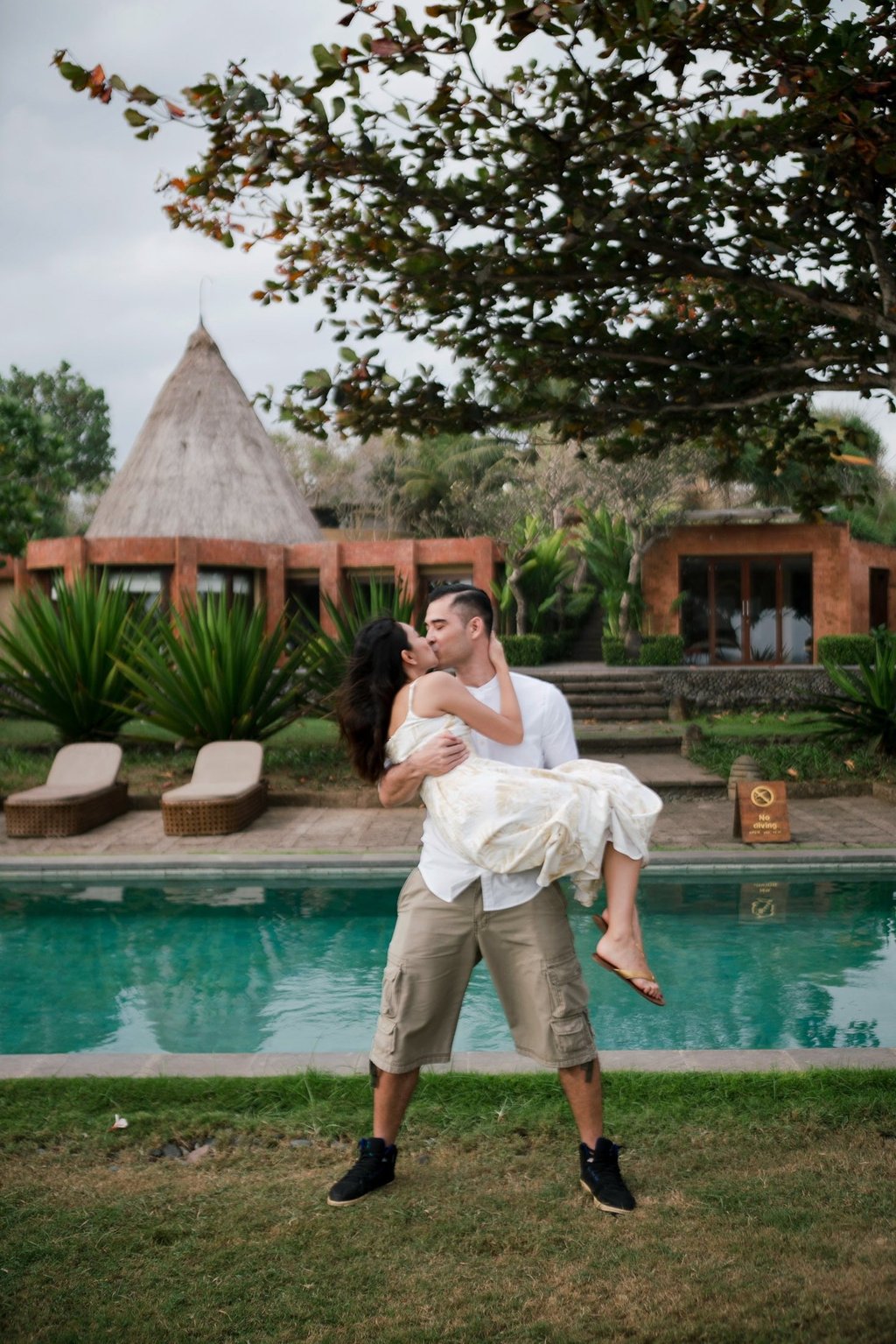 Intimate couple session at Waka Gangga Tabanan featuring groom lifting bride by the pool in West Bali luxury resort