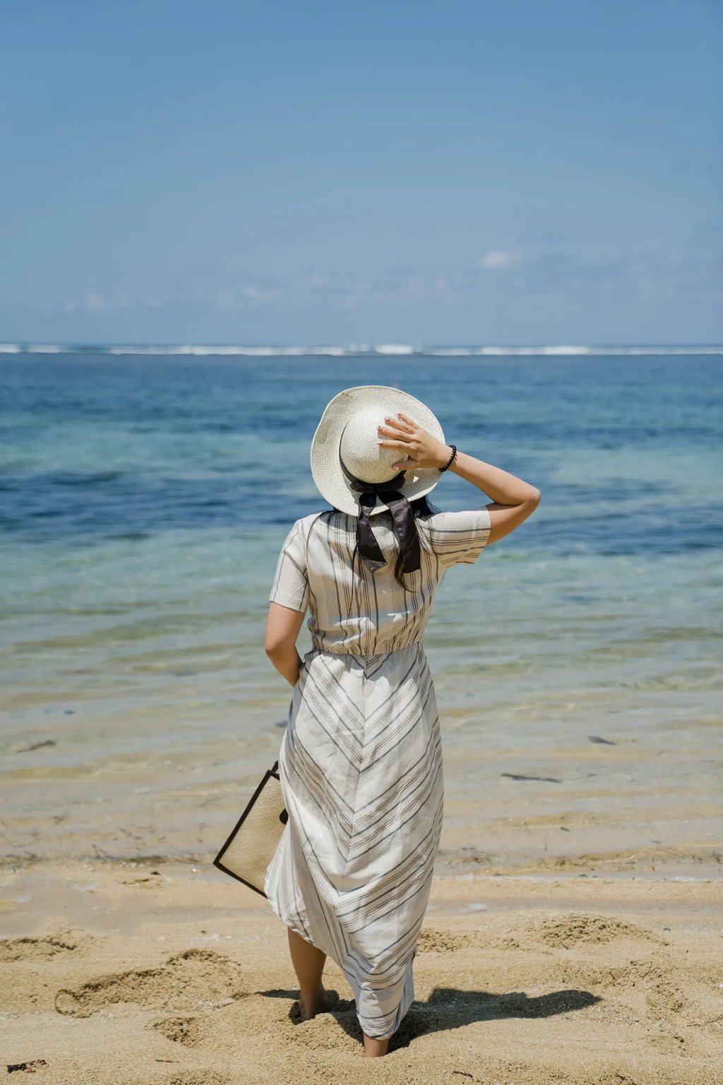 Woman walking along the shoreline during a portrait session at Samabe Bali Suites & Villas in Nusa Dua.