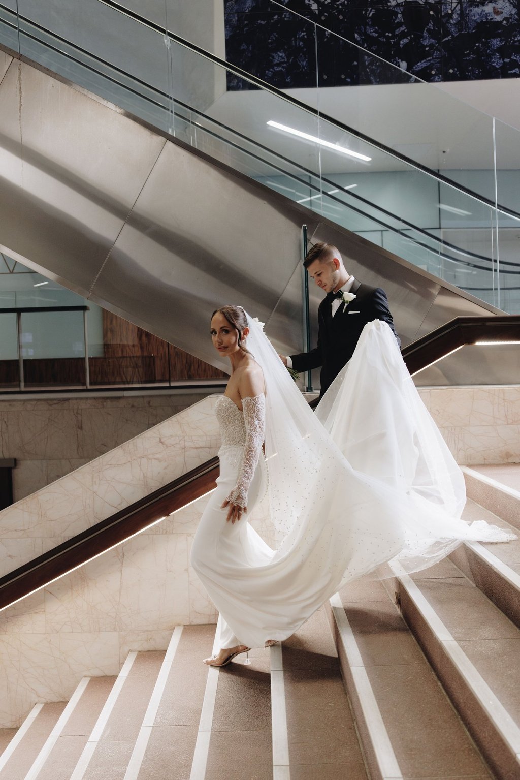 a bride and groom walking down a flight of stairs