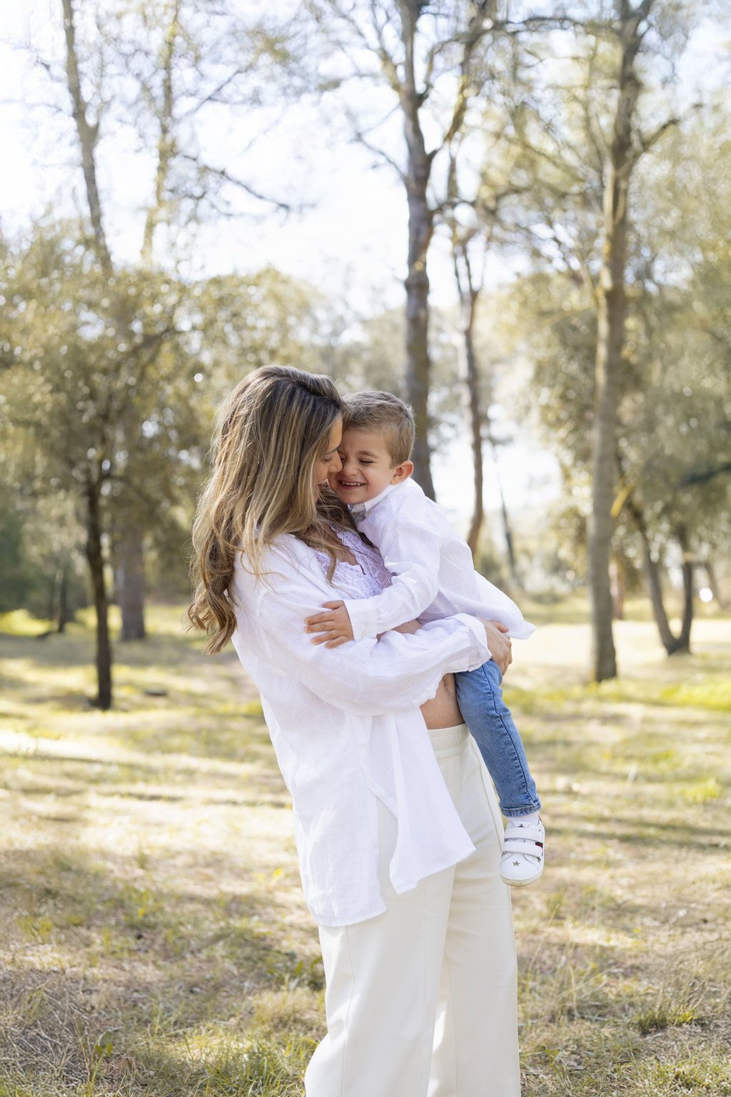 Sessió de fotos d'embaràs a Girona amb una dona embarassada abraçant fill un entorn natural exterior