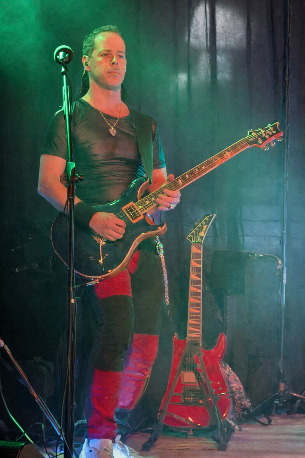 Dan performing live on stage with a blue PRS electric guitar under green stage lighting.