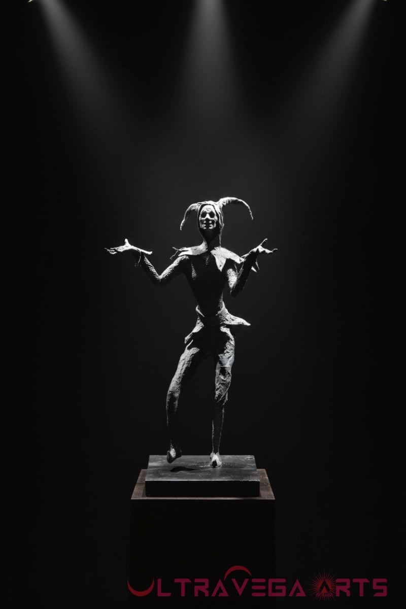 Harlequin Figurative Sculpture in Paper Mache on dark pedestal, spot lit with dark background