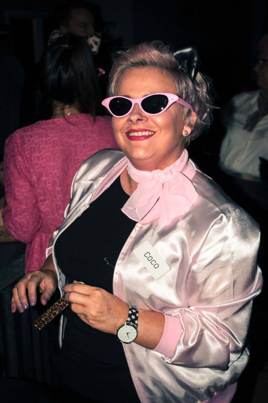 a woman is dressed in 1950s costume for a murder mystery party. She is wearing sunglasses and kitten ears.