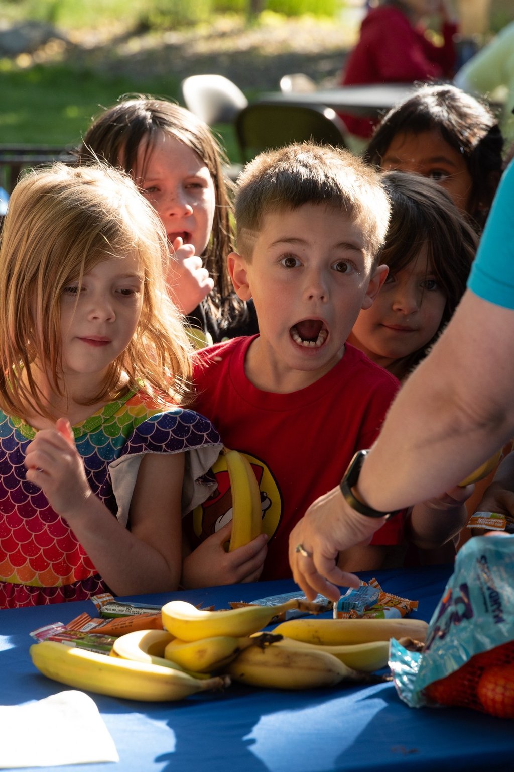 A group of children at a breakfast station getting bananas!