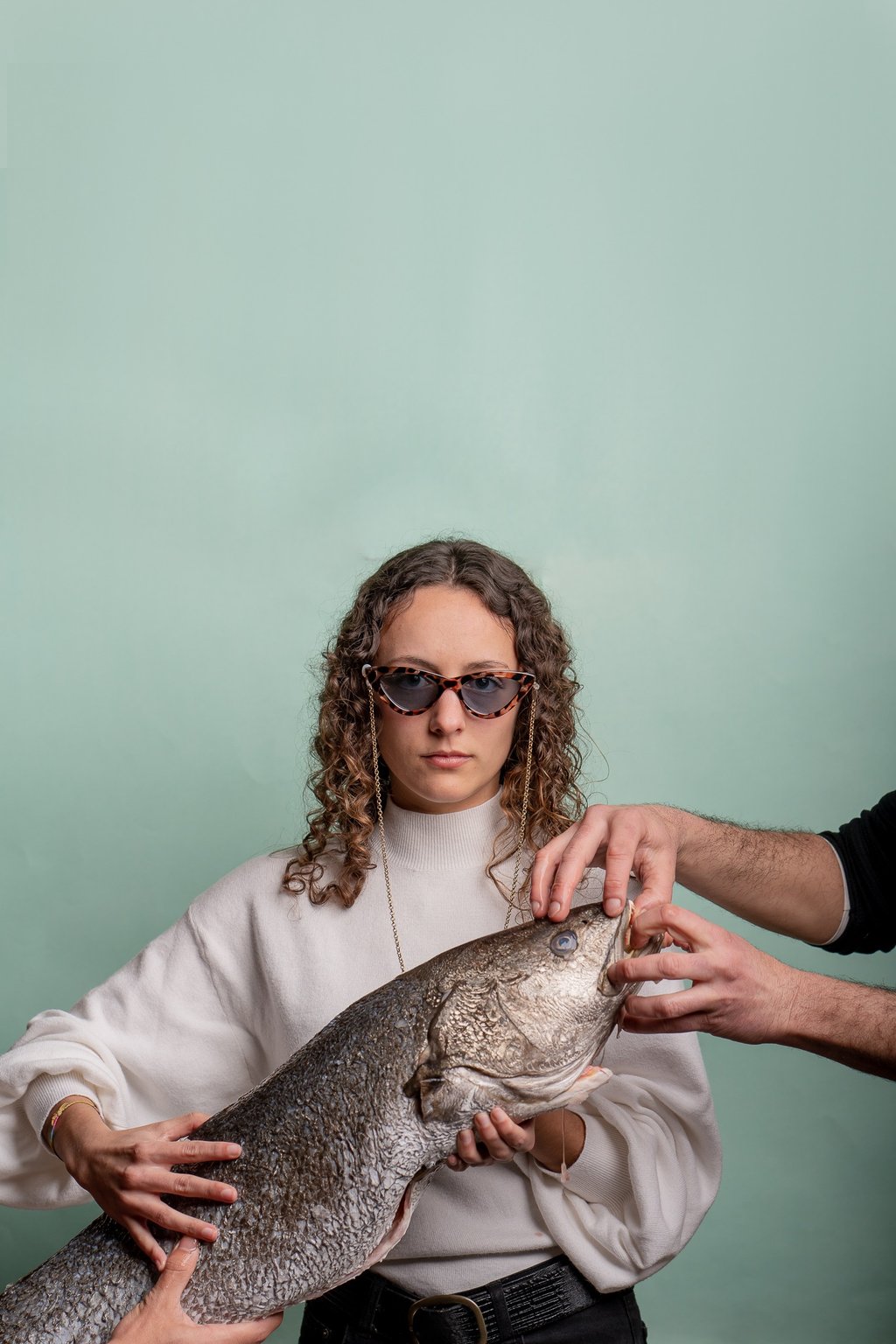 fotografía corporativa de gastronomia de una mujer sosteniendo un pez con gafas de sol