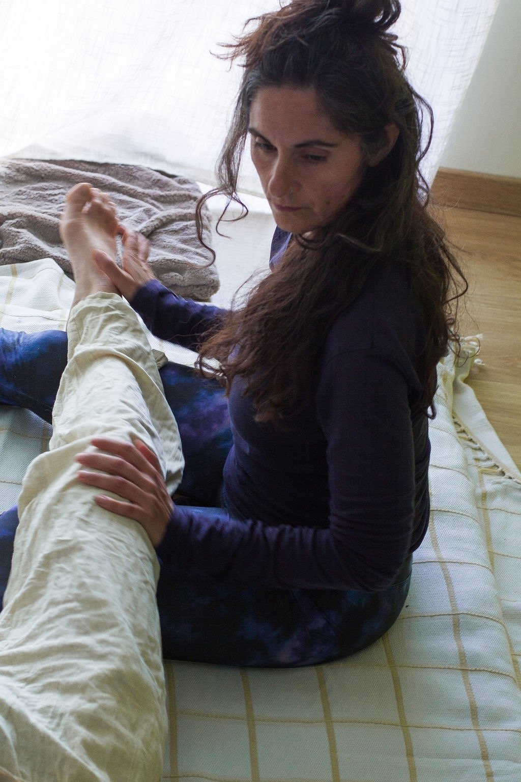 Juliette Maggu in Thai Yoga Massage Position mit Händen am Bein der massiertes Person 