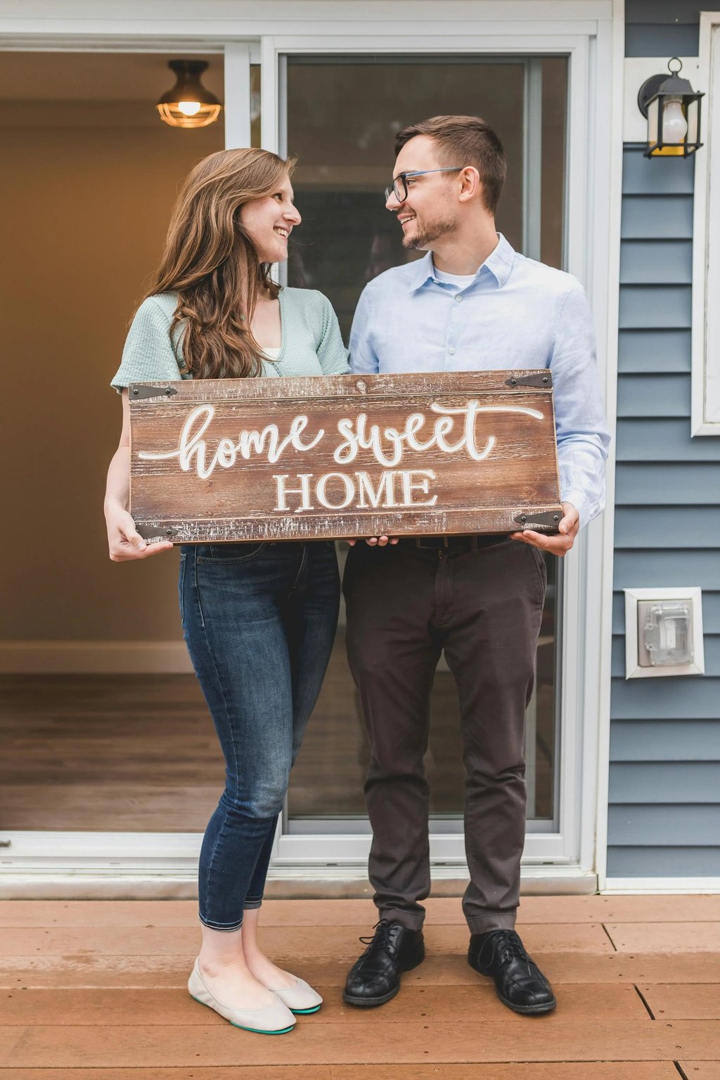 Happy homeowners with home sweet home sign, representing the excitement of first-time home buyers