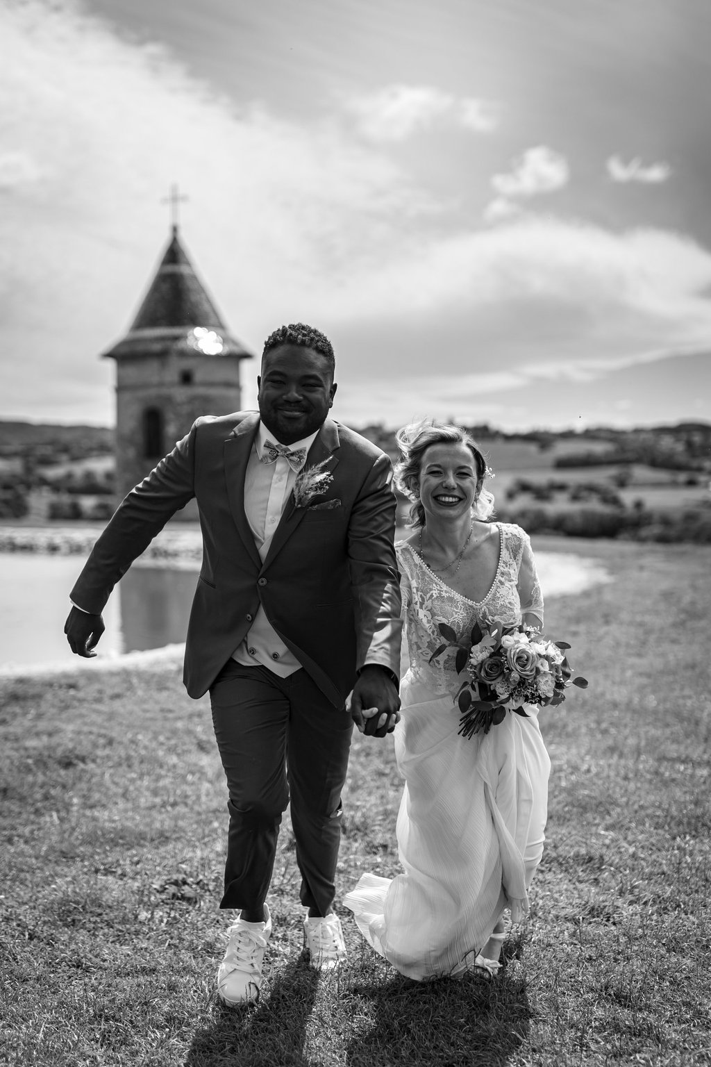 a bride and groom running on grass